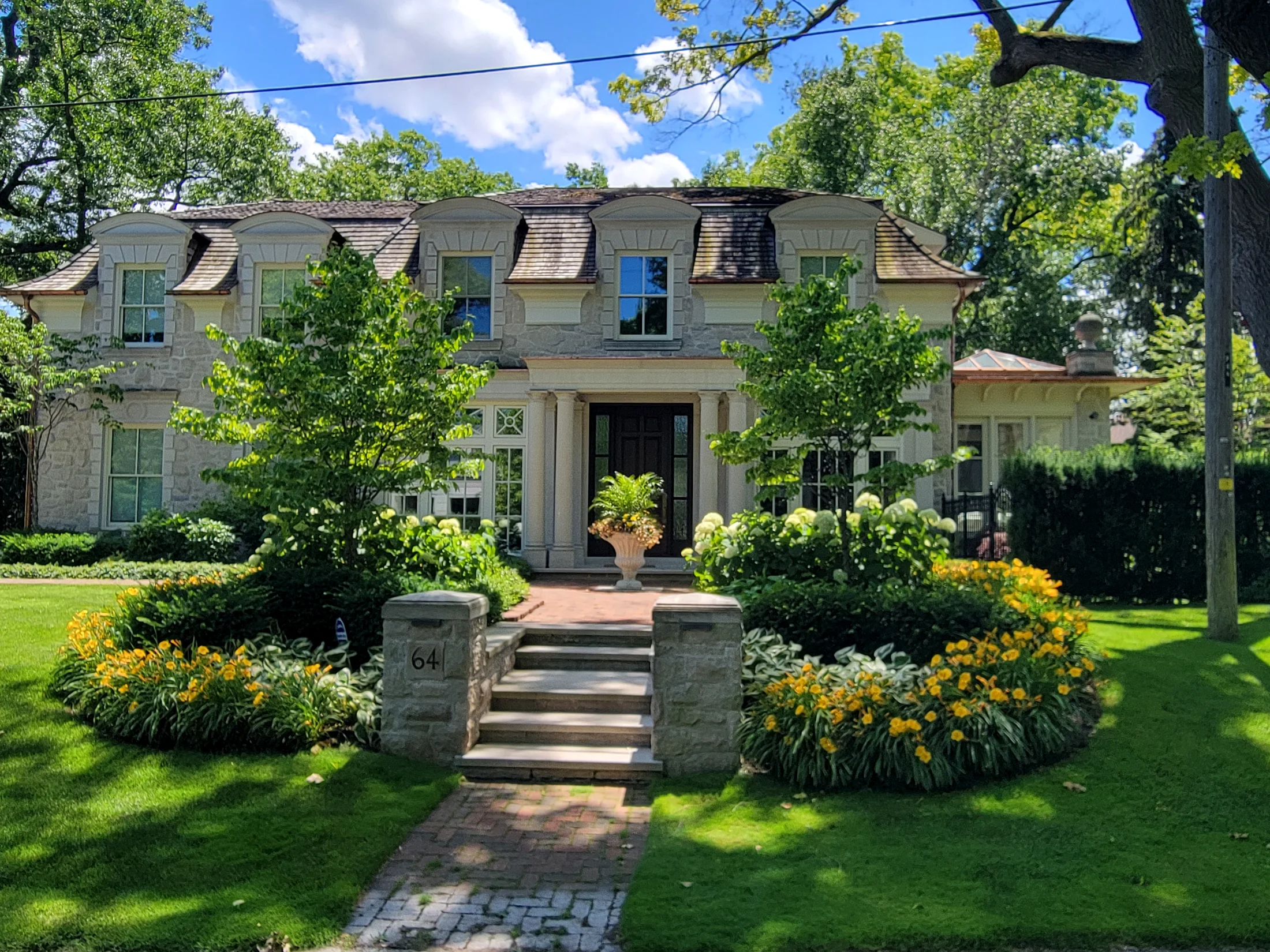 Premium residential front landscape with manicured lawn and gardens.